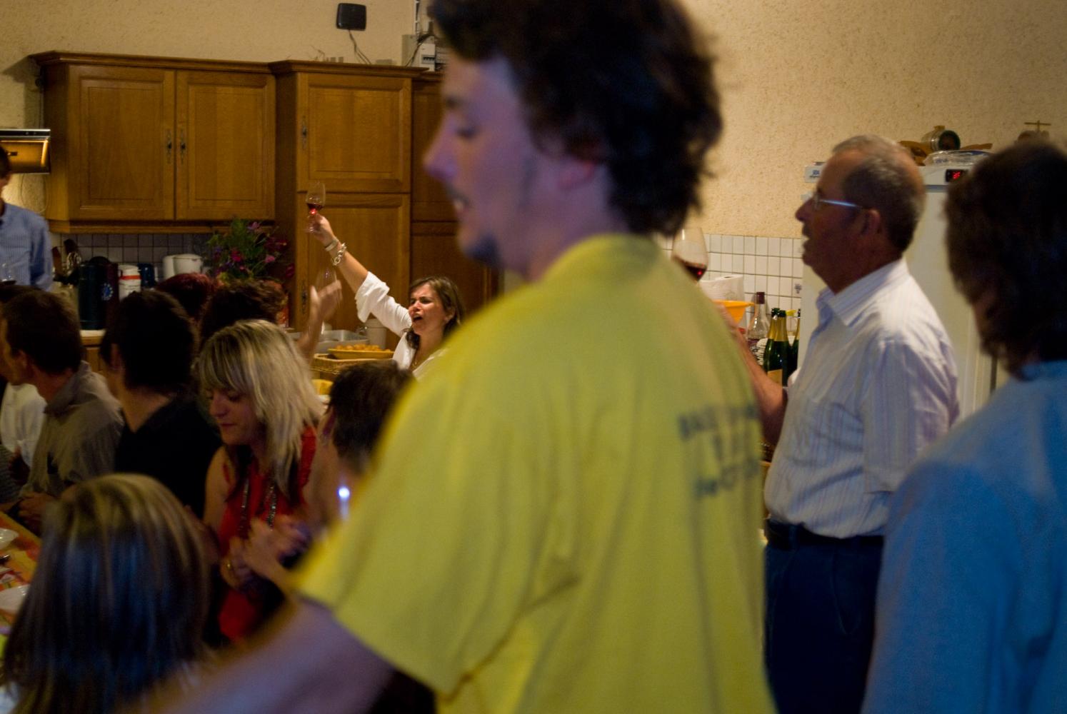 A la paulée, derrière quelques personnes debout, assise à une des longues tables, Marie-Anne Pillot lève son verre avec conviction. Chassagne-Montrachet, Bourgogne, septembre 2009.